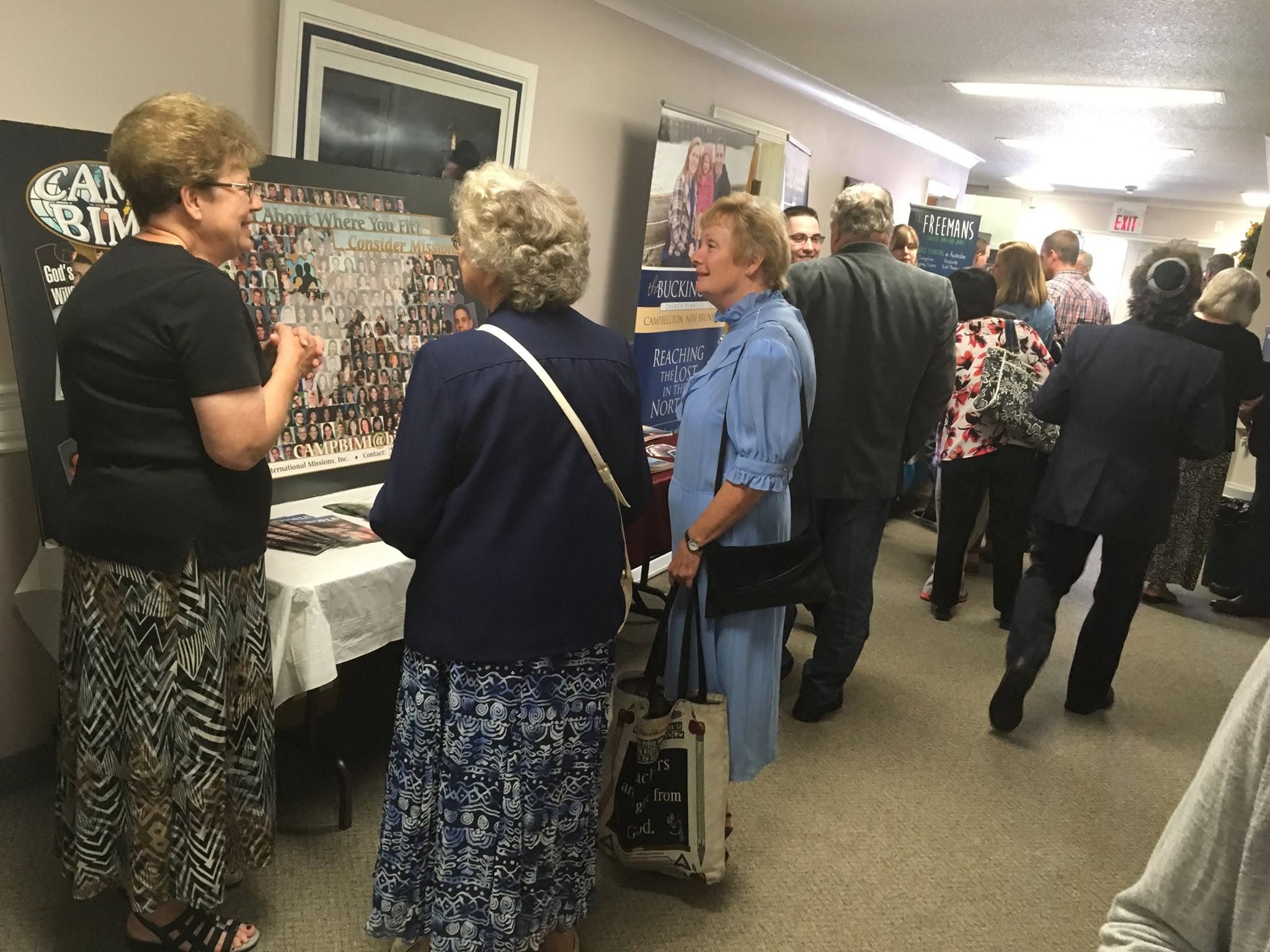 Conversations beside missions display tables at church.